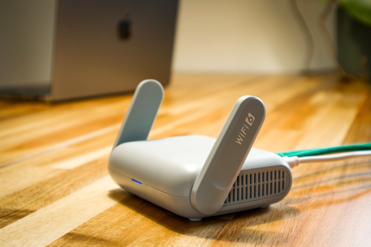 services-04 A sleek WiFi 6 router with antennas and cable on a wooden desk, perfect for modern home networks.